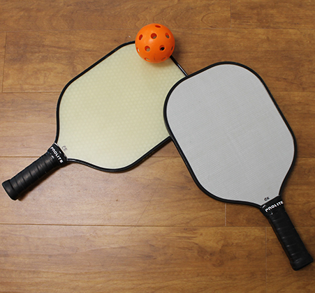 two pickleball paddles and a ball